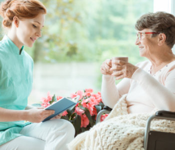 Caregiver reading a book to an elder woman