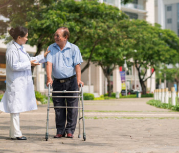 Doctor helping elder man to walk